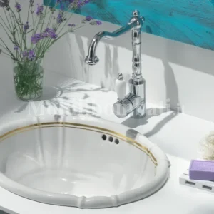 lavabo in ceramica bianca con doppio filetto in oro zecchino in un bagno bianco e con dettagli azzurri.